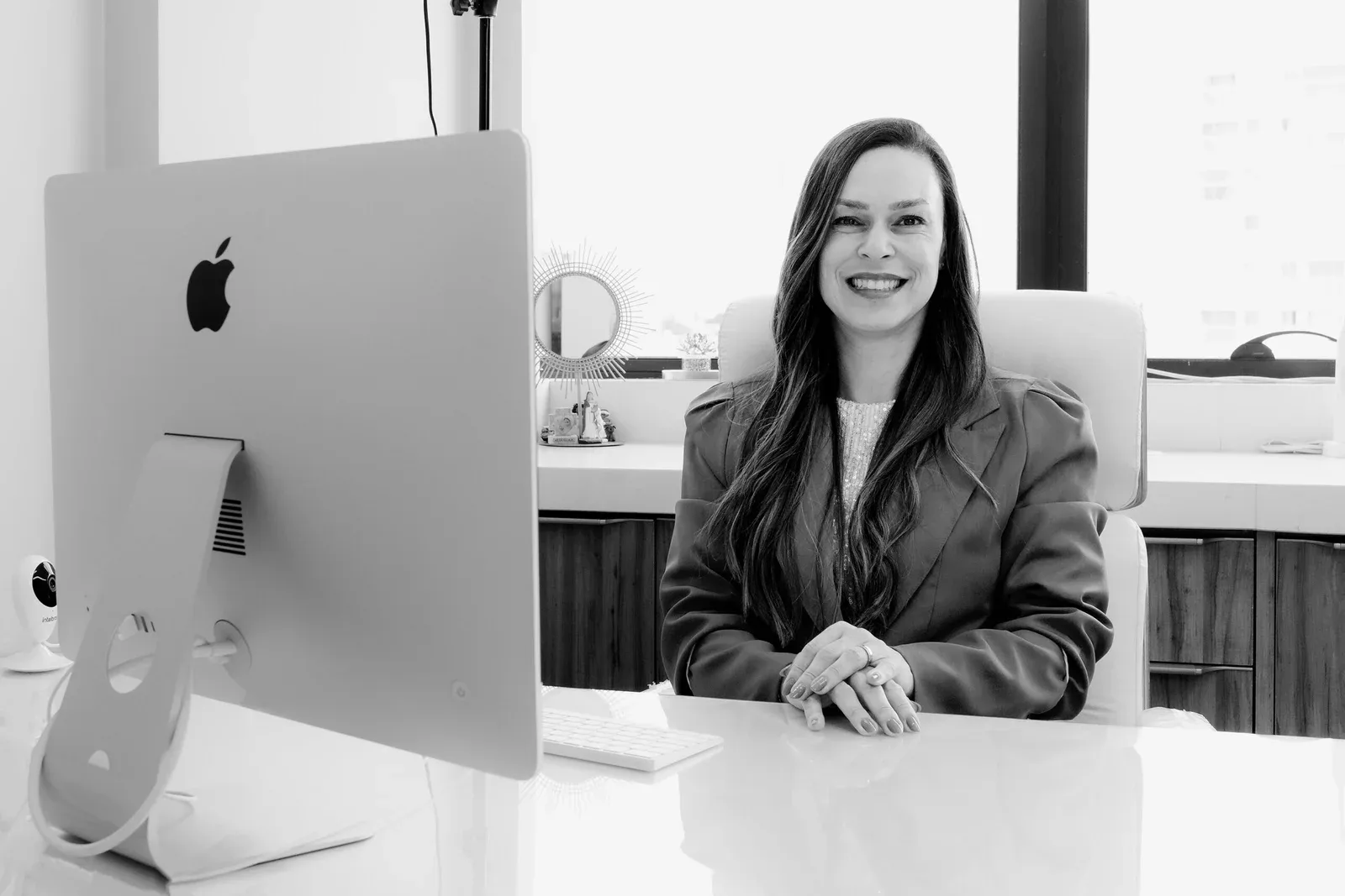 Dra. Mirian Bustillo à mesa do consultório, em frente à janela